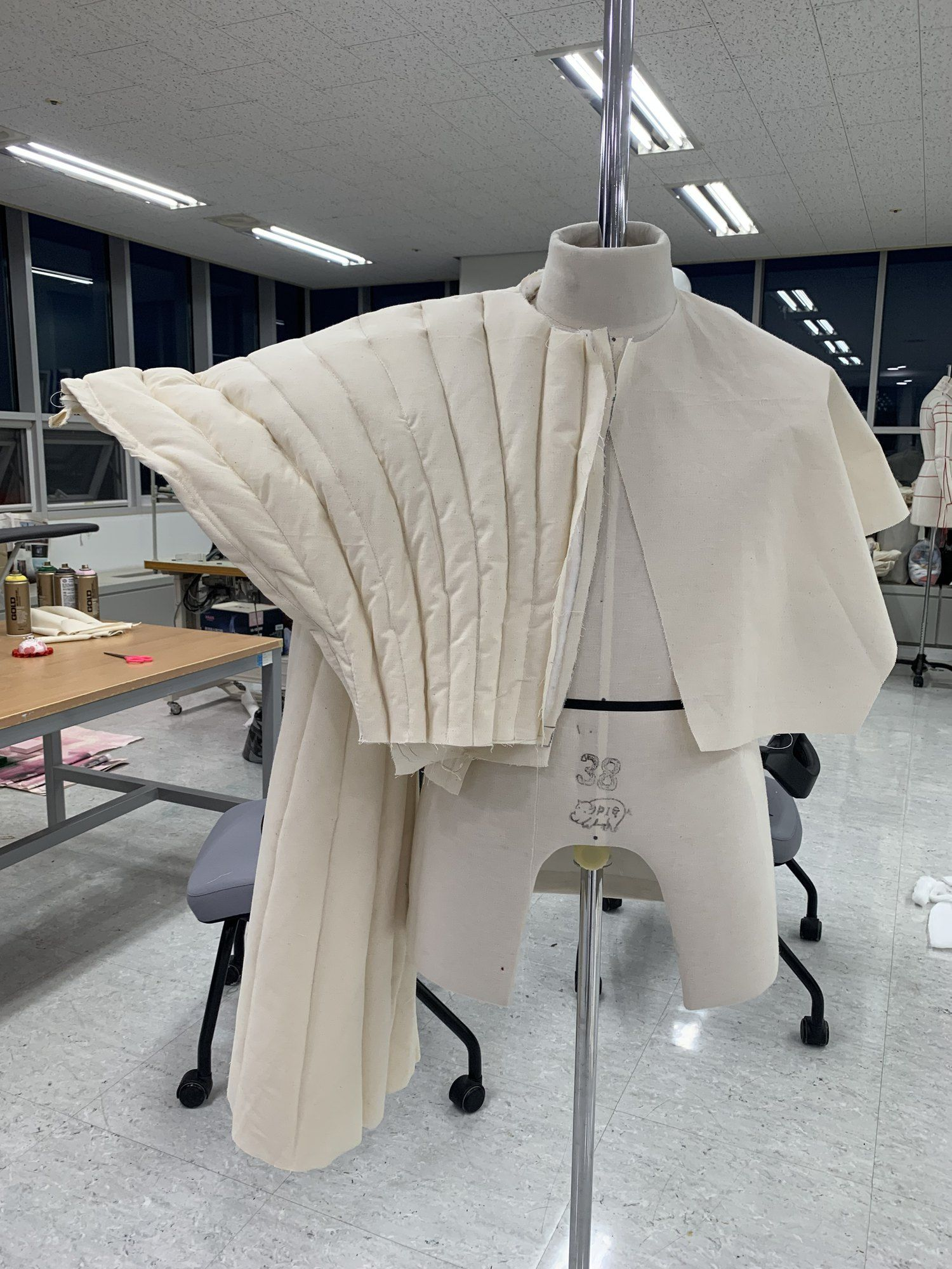 Calico toile of a pleated puffer cape on a mannequin