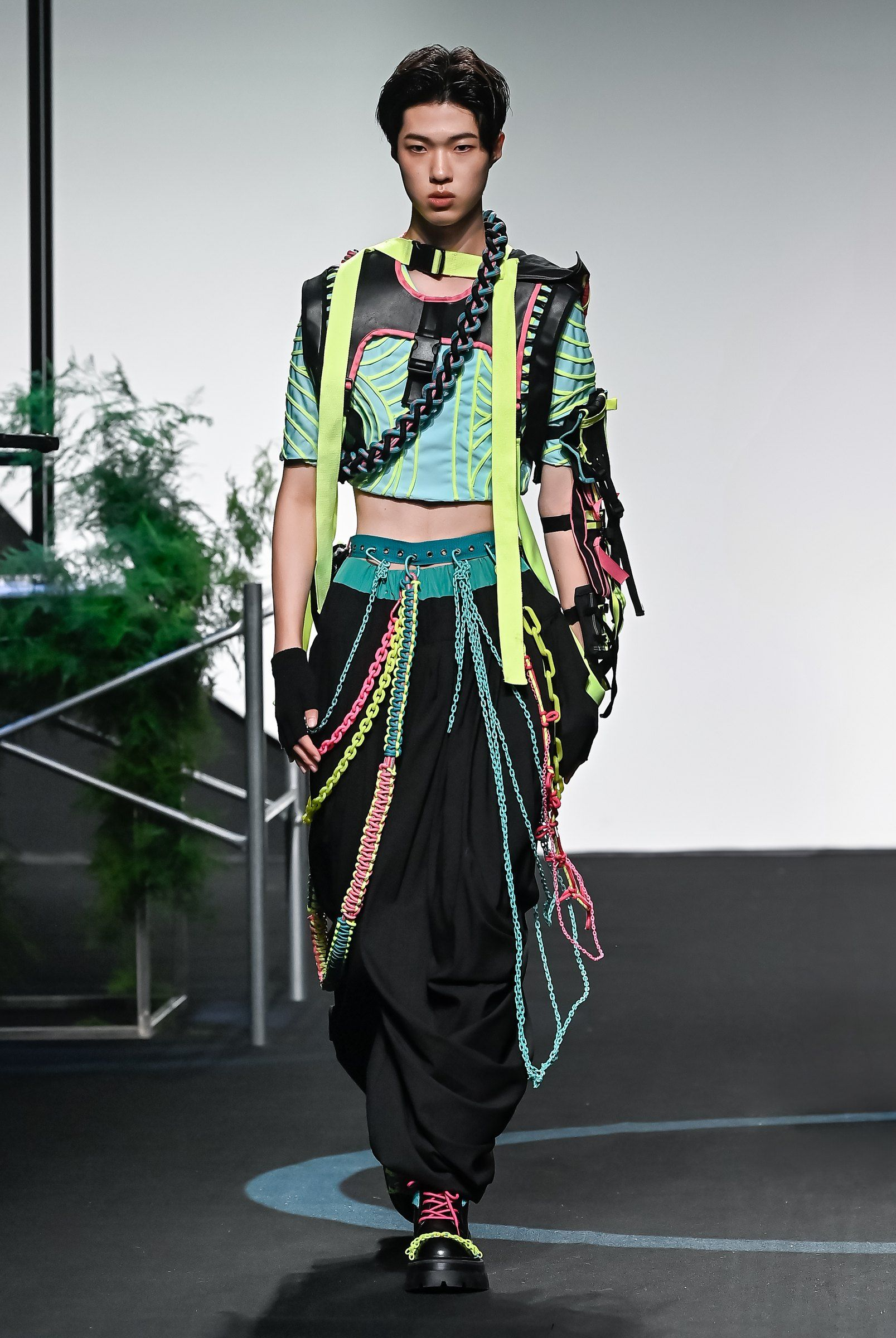 Look 02 walking: harness crop top with cyan quilting and lime straps, black harem trousers with rope