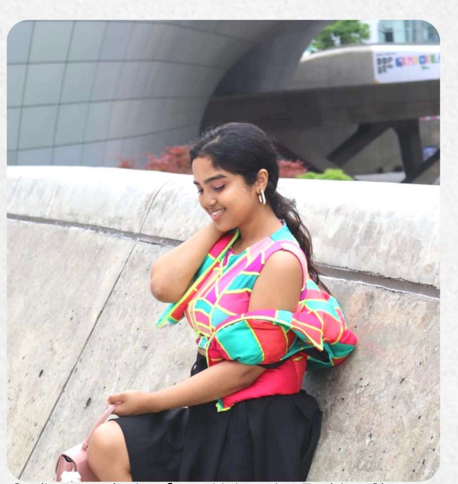 Etosha Paul seated outside Dongdaemun Design Plaza in Seoul, wearing her own patchwork top